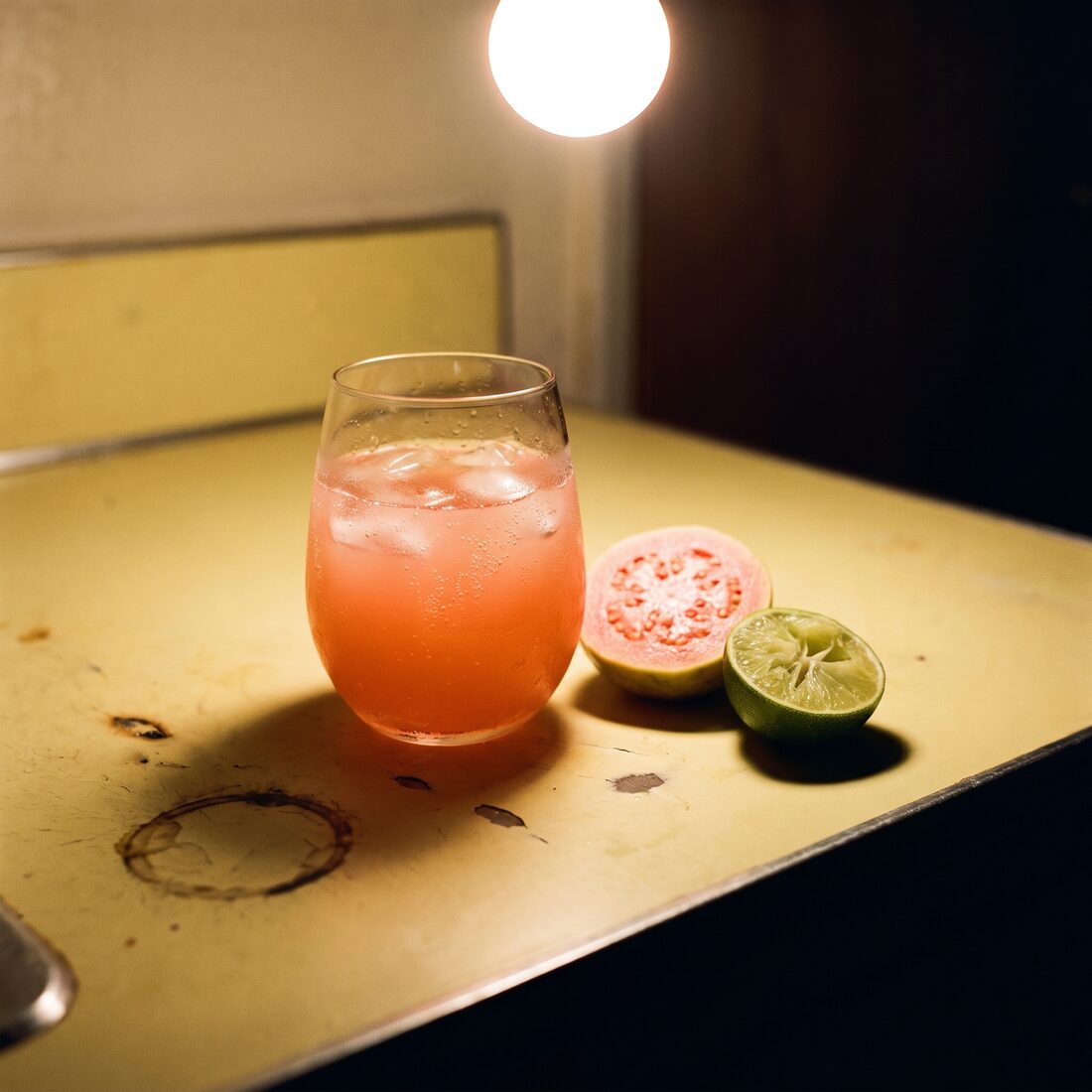A Guava Rose on a yellow kitchen table under a single warm bulb